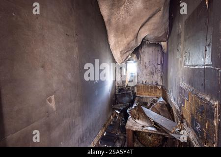 Photo of an extremely run down property that has had a massive fire showing the burnt walls floor and ceiling in the bathroom and the charded bathroom Stock Photo