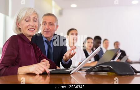 Professional mature male and female colleagues having business discussion during meeting at office Stock Photo