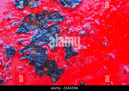 A red surface with black spots and splatters. The surface is old and worn, with a sense of decay and abandonment Stock Photo