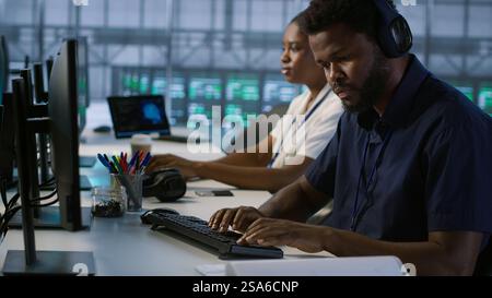 Engineer in server room looking over documents, developing disaster recovery plans ensuring minimal downtime. Worker reading paperwork in data center, using analytics to monitor performance, camera A Stock Photo
