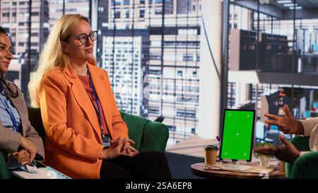 Group of businesswomen using green screen mockup on tablet in a briefing meeting, exchanging ideas and details about a future project. Ambitious female leaders planning a strategy. Camera A. Stock Photo