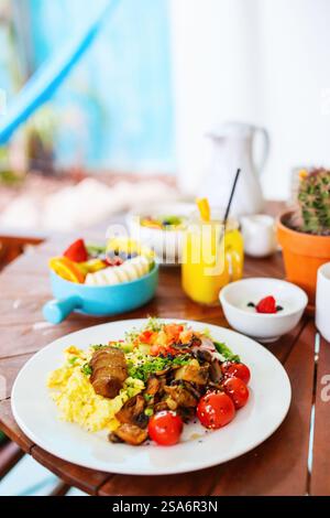 Vegetarian breakfast with scrambled eggs, roasted potatoes, plant-based sausage, sauteed mushrooms and cherry tomatoes Stock Photo