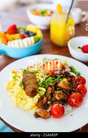 Vegetarian breakfast with scrambled eggs, roasted potatoes, plant-based sausage, sauteed mushrooms and cherry tomatoes Stock Photo
