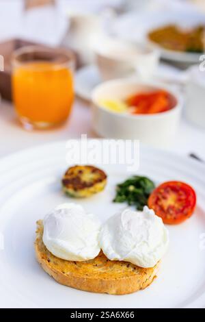 Poached eggs served for breakfast with vegetables, coffee and juice Stock Photo