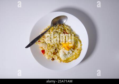 Plate of Fried Rice and Egg with Spoon on Light Background Stock Photo