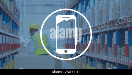 Image of smartphone icon in circle over caucasian man working in warehouse Stock Photo