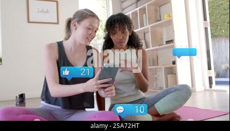Image of social media text and icons over diverse girlfriends using smartphone Stock Photo