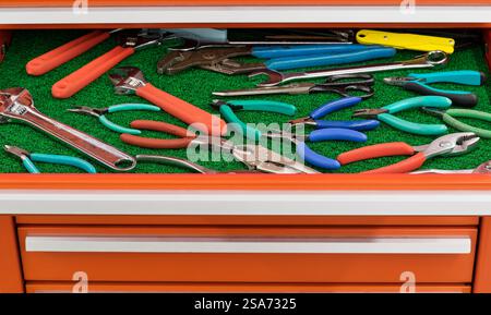Assorted pliers wrench clamping tools displayed in open toolbox drawer. Stock Photo