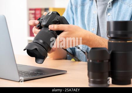Close up of photographer man hands with laptop checking dslr camera on a desk at home Stock Photo