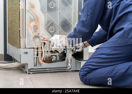 Shot of a young man repairing dishwasher in a home Stock Photo