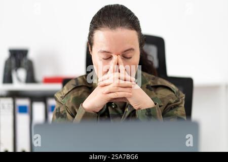 Shot of a female soldier looking stressed out while working in an office Stock Photo