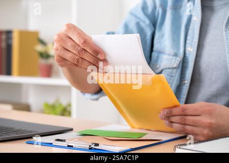 Close up of man hands opening a letter on a padded envelope on a desk at home Stock Photo