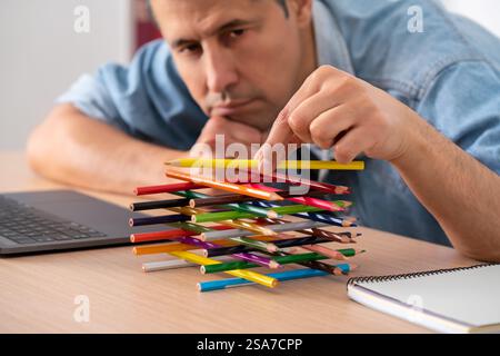 Close-up of the hand of a bored lazy worker with his hands wasting time playing with pens sitting at a desk in the office Stock Photo