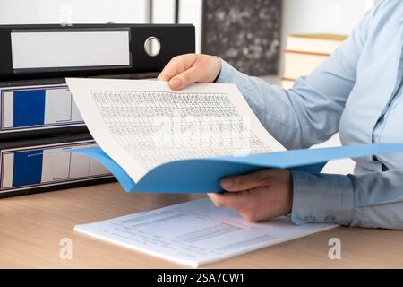 Close up of woman hands checking documents on folders sitting on a desk at office Stock Photo