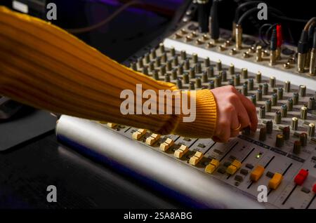 Sound engineer adjusting audio levels on a mixing console in a recording studio Stock Photo