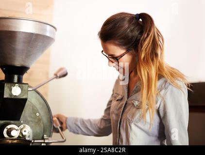 Coffee, woman and roasting machine for production, quality control and manufacturing process at small business. Factory, equipment and barista with Stock Photo