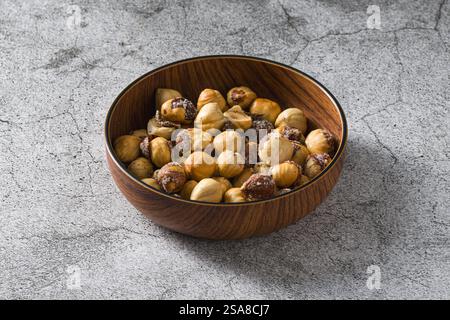 Roasted salted hazelnuts in wooden bowl on stone table Stock Photo
