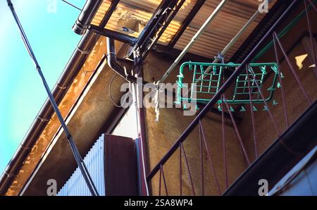 An empty plastic hanger for drying clothes hanging over the second-story balcony of an aged apartment building in west Tokyo Stock Photo