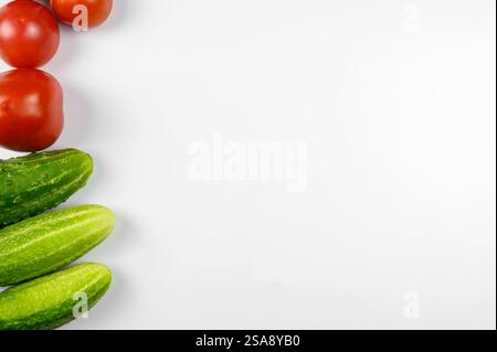 Layout of ripe tomatoes and cucumbers on a white background. The concept of cooking, organic vegetables. Top view. Stock Photo