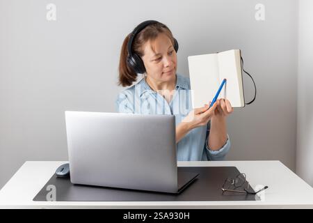 Happy young woman using laptop, watching webinar, studying online, looking at pc screen learning web classes or having virtual call meeting remote wor Stock Photo