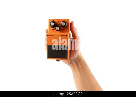 Male hand holding an orange guitar effects pedal isolated on white background cutout Stock Photo