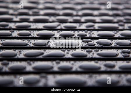 Accumulation of large water drops on black metal bar - Background pattern Stock Photo