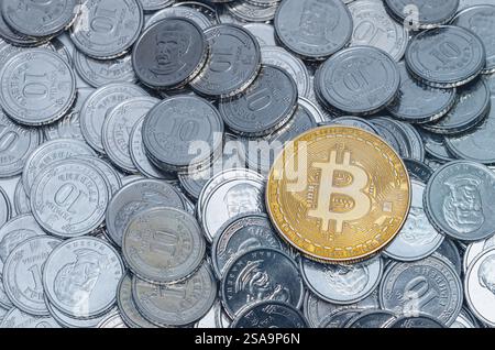 Golden Bitcoin on silver coins. Money background. Symbolic integration of cryptocurrency into modernity Stock Photo