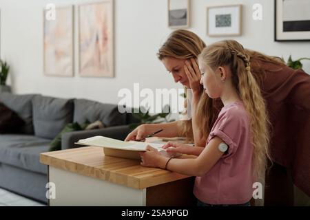 Mother and Daughter Doing Homework in Kitchen Stock Photo
