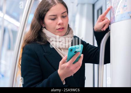 Young Woman Checking Subway Map While Using Smartphone Stock Photo