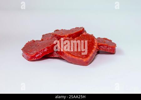 Heart shaped pumpkin candy, with a shiny texture and intense red color, arranged on a light surface. Stock Photo