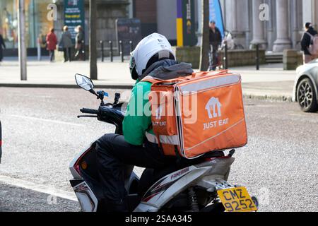 just eat delivery driver sitting on moped in belfast city centre looking at his phone belfast, northern ireland, uk Stock Photo