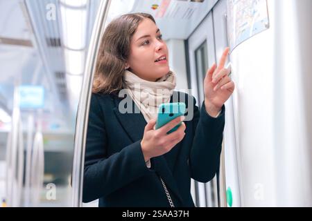 Young Woman Checking Subway Map While Using Smartphone Stock Photo