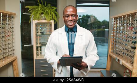 Professional Optometrist in Modern Office Using Digital Tablet Standing Among Eyeglasses Stock Photo