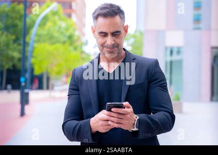 Confident businessman using smartphone outdoors, Stock Photo