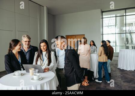 Diverse group of business professionals collaborating and networking in a conference environment, focused on teamwork and idea exchange. Emphasizing c Stock Photo