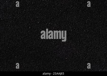Creative natural textured background, small black pebbles or coarse sand, candle wax in an even layer on the surface, place for text Stock Photo