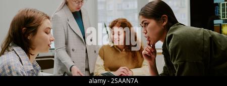 Group of colleagues engaging in discussion during work meeting in office setting. Team members sharing ideas and working together on project tasks Stock Photo