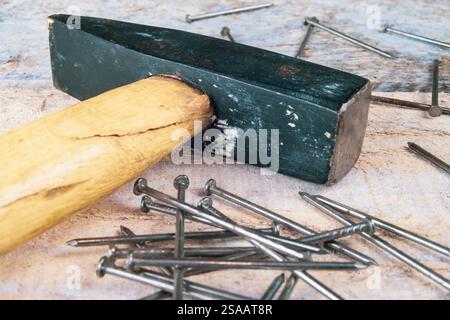 Hammer and a pile of nails on an old wooden table. Laying flat on a rustic old white painted wooden table repaired. DIY carpentry Stock Photo