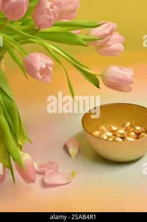 Easter eggs and pink tulips on a coloured background Stock Photo