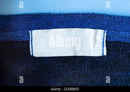 White blank laundry care clothes label on blue polyester sport shirt background Stock Photo