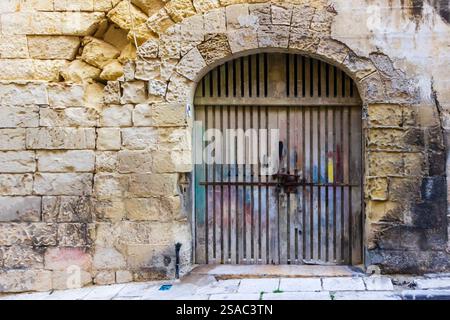 Historic Weathered Stone Wall with Rusted Locked Metal Gate in Urban Setting Stock Photo