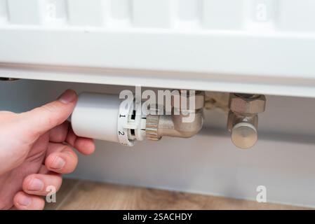 Close-up of male hands regulating the thermostat on the radiator Stock Photo