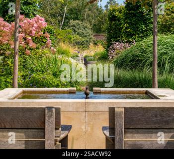 Formal square stone raised pool with  small central fountain,feeding a central rill in the RHS Bridgewater’s Paradise Garden. Stock Photo
