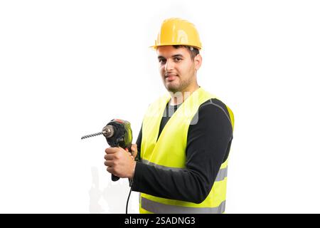 Male constructor wearing yellow safety hardhat and fluorescent vest using electric drill at trades building work isolated on white background Stock Photo