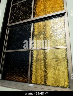 Objects behind ornate windows with golden textured glass panes in the afternoon light Stock Photo