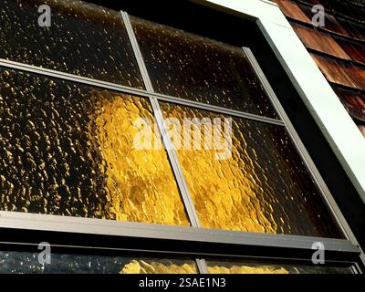 Objects behind ornate windows with golden textured glass panes in the afternoon light Stock Photo
