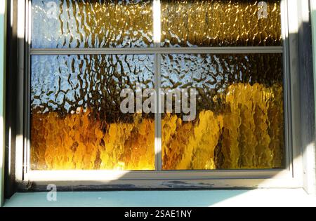 Objects behind ornate windows with golden textured glass panes in the afternoon light Stock Photo