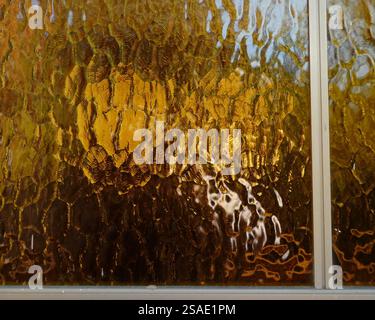 Objects behind ornate windows with golden textured glass panes in the afternoon light Stock Photo