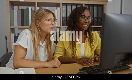 Young women working in office discussing serious matter at computer showing workplace dynamics and professionalism Stock Photo