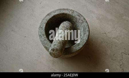 Mortar resting on concrete surface, highlighting its rough texture and robust design, ideal for kitchen or medicinal grinding applications in various Stock Photo